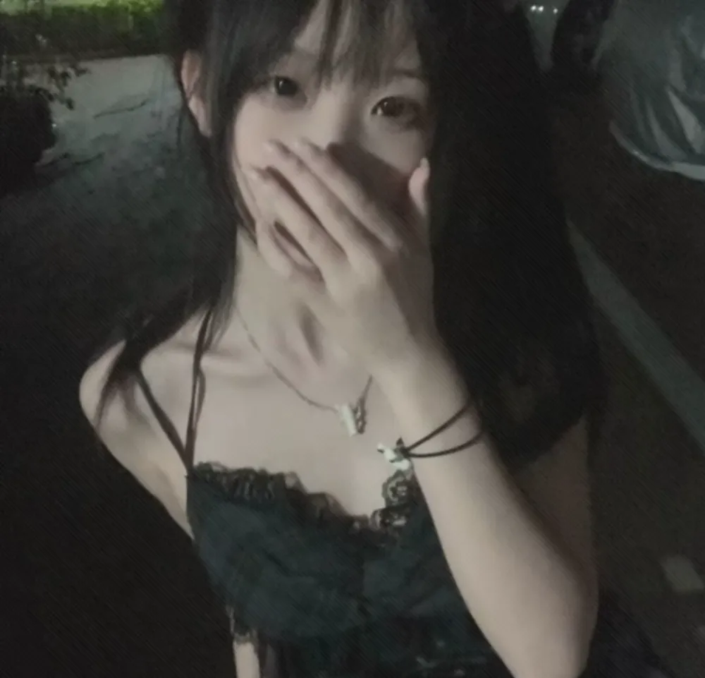 ｜抖音创作者公开 黑发人物穿深色吊带上衣，以手遮住嘴部，在暗色环境中进行近距离自拍