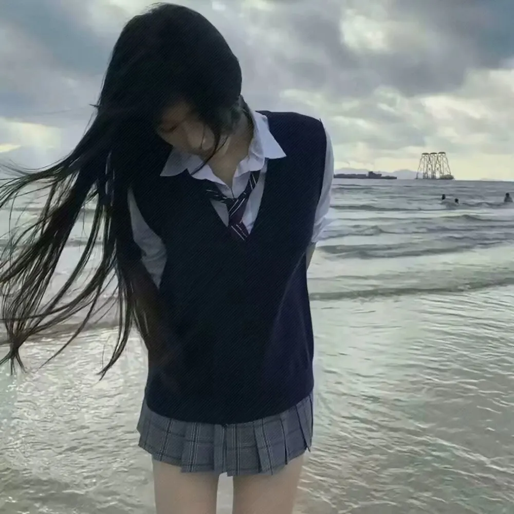 ｜抖音创作者公开 长黑发人物穿白衬衫、深色针织背心和格纹裙站在海边