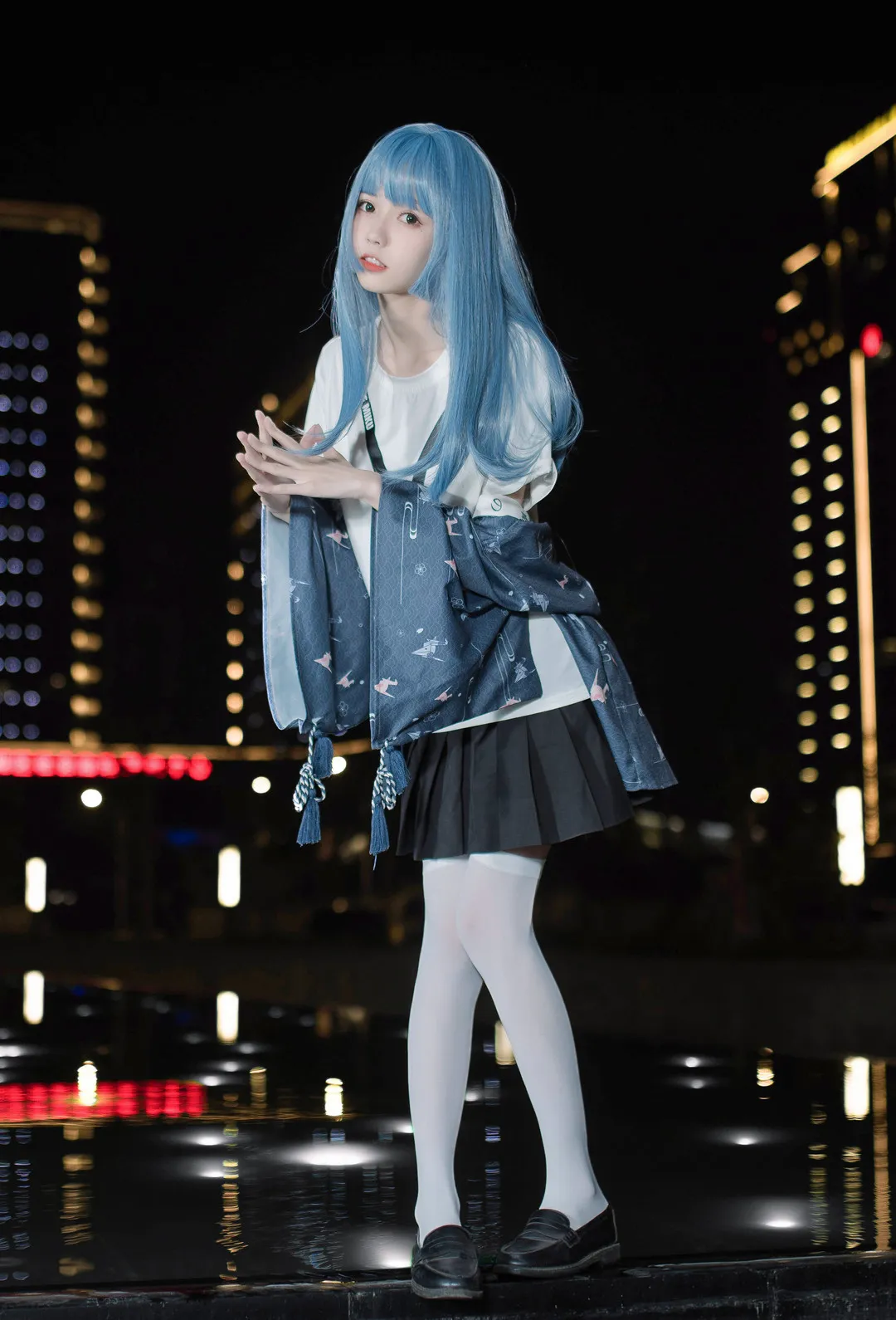 微博公开账号与写真风格 蓝色长发人物穿白色上衣和深色短裙，站在夜间城市灯光与水面倒影前