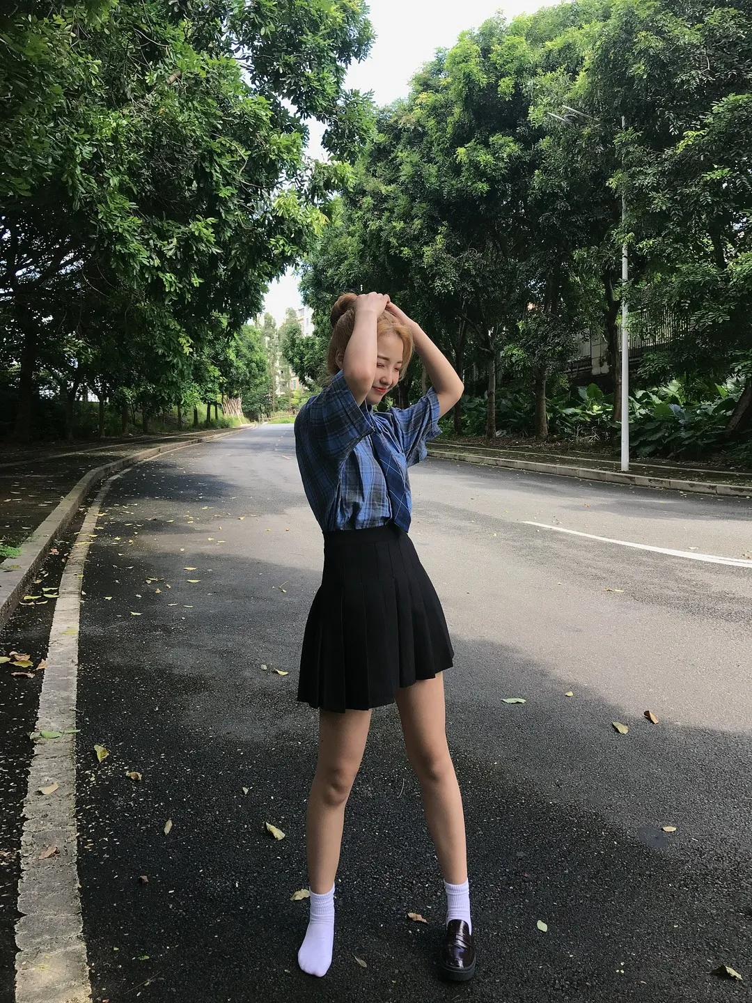林荫柏油马路金色短发蓝色短袖衬衫配黑色百褶超短裙双手抚发立姿
