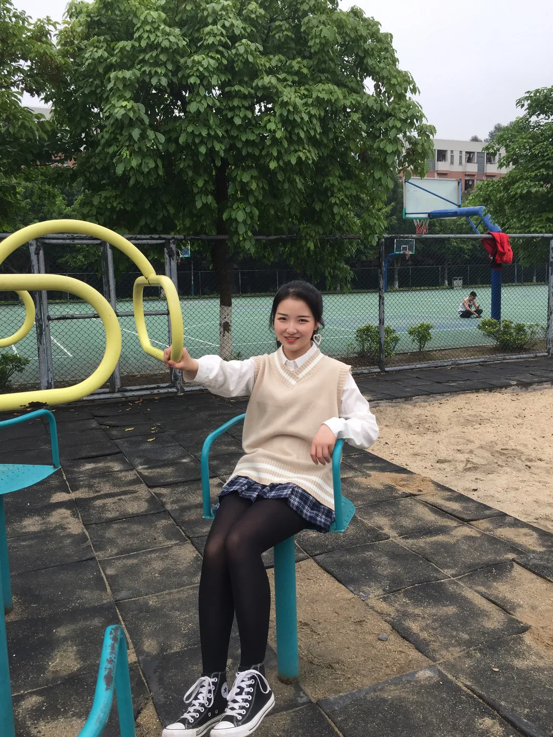 篮球场旁游乐设施长椅米白马甲白衬衫黑百褶裙黑丝配高帮帆布鞋坐姿