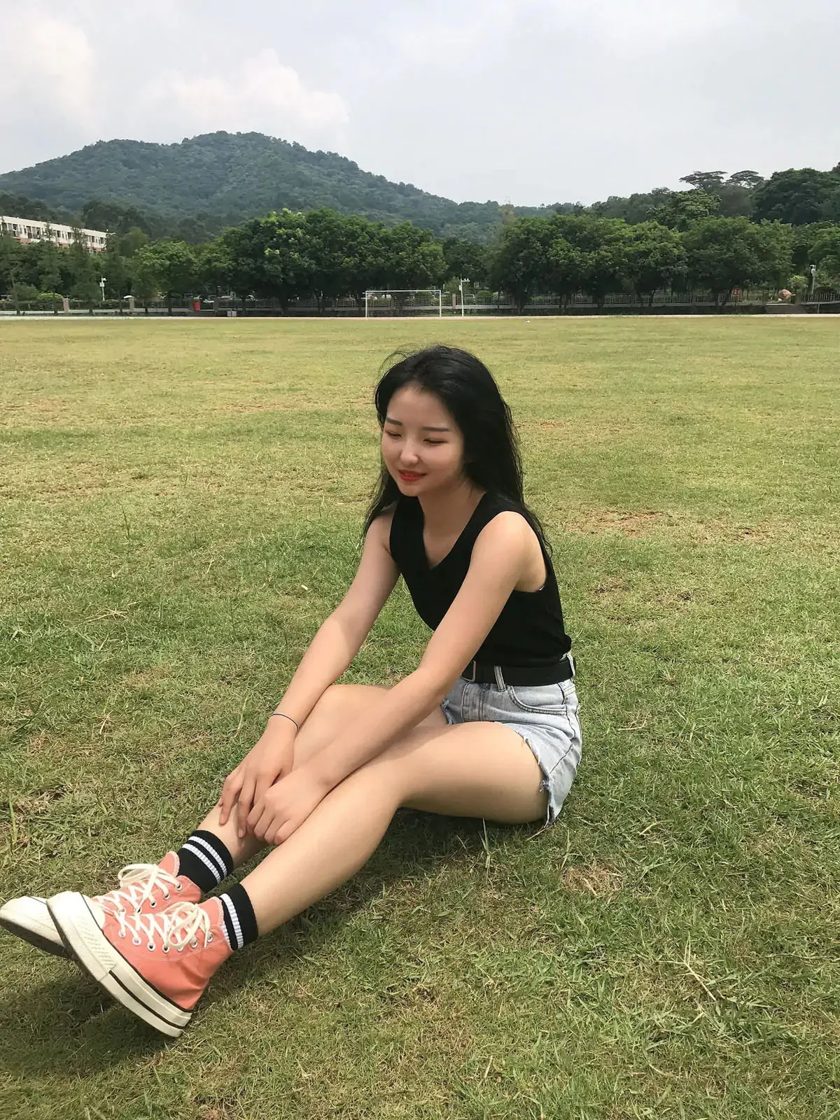 黑色无袖紧身背心配浅蓝牛仔短裤粉白高帮帆布鞋校园草坪席地侧坐
